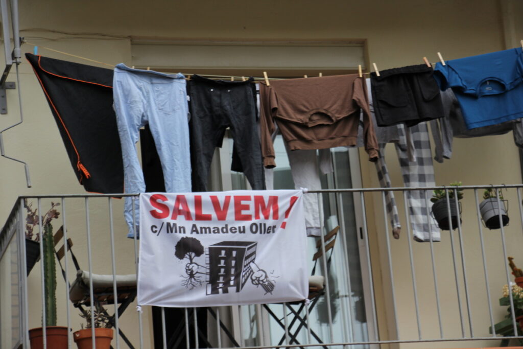 Protestas y ropa tendida en un balcón cercano al carrer d’Amadeu Oller